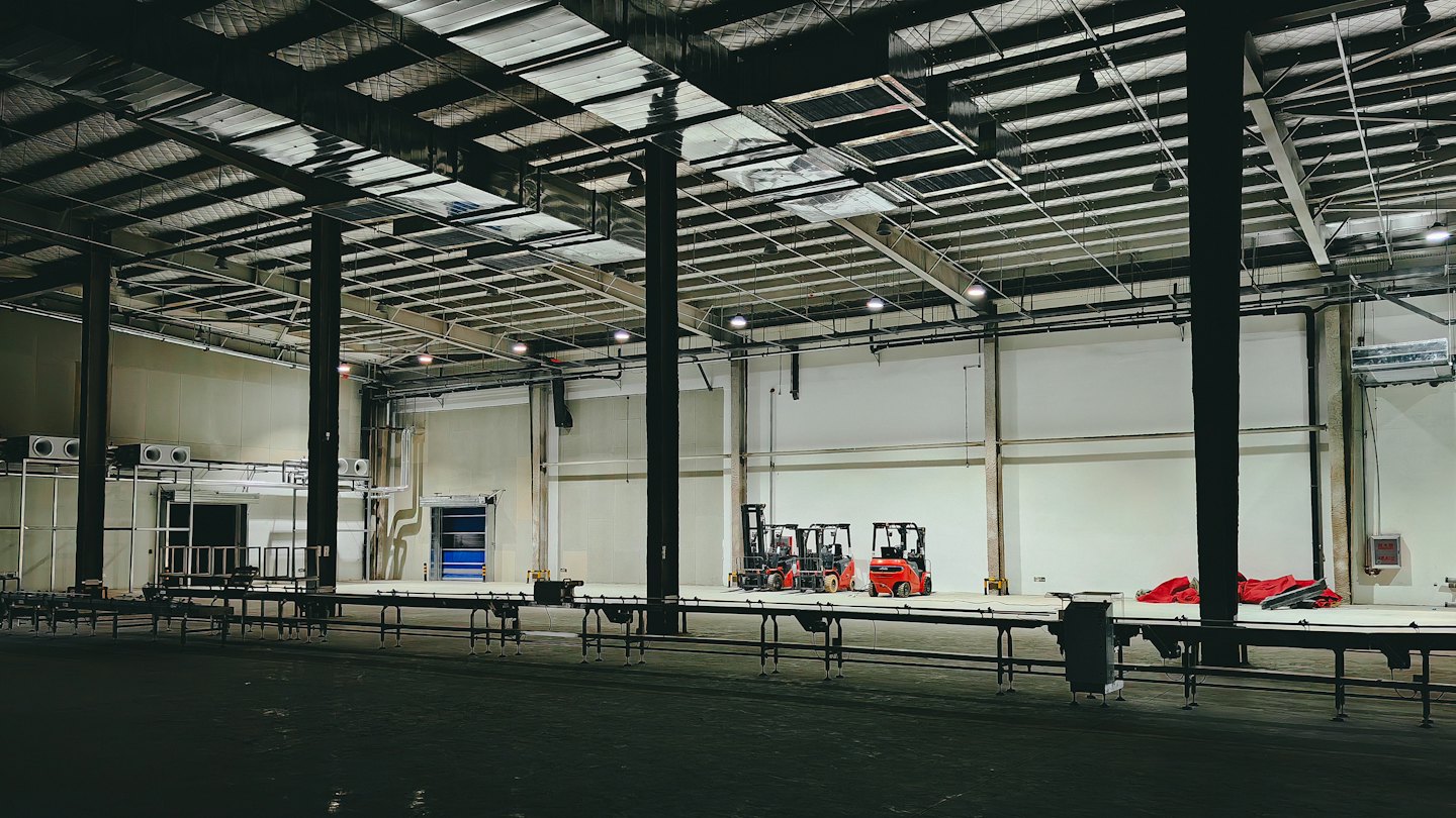 Red forklifts are parked inside a modern industrial warehouse.
